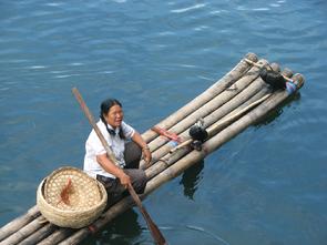 Woman and cormorant sitting on a boat made from bamboo